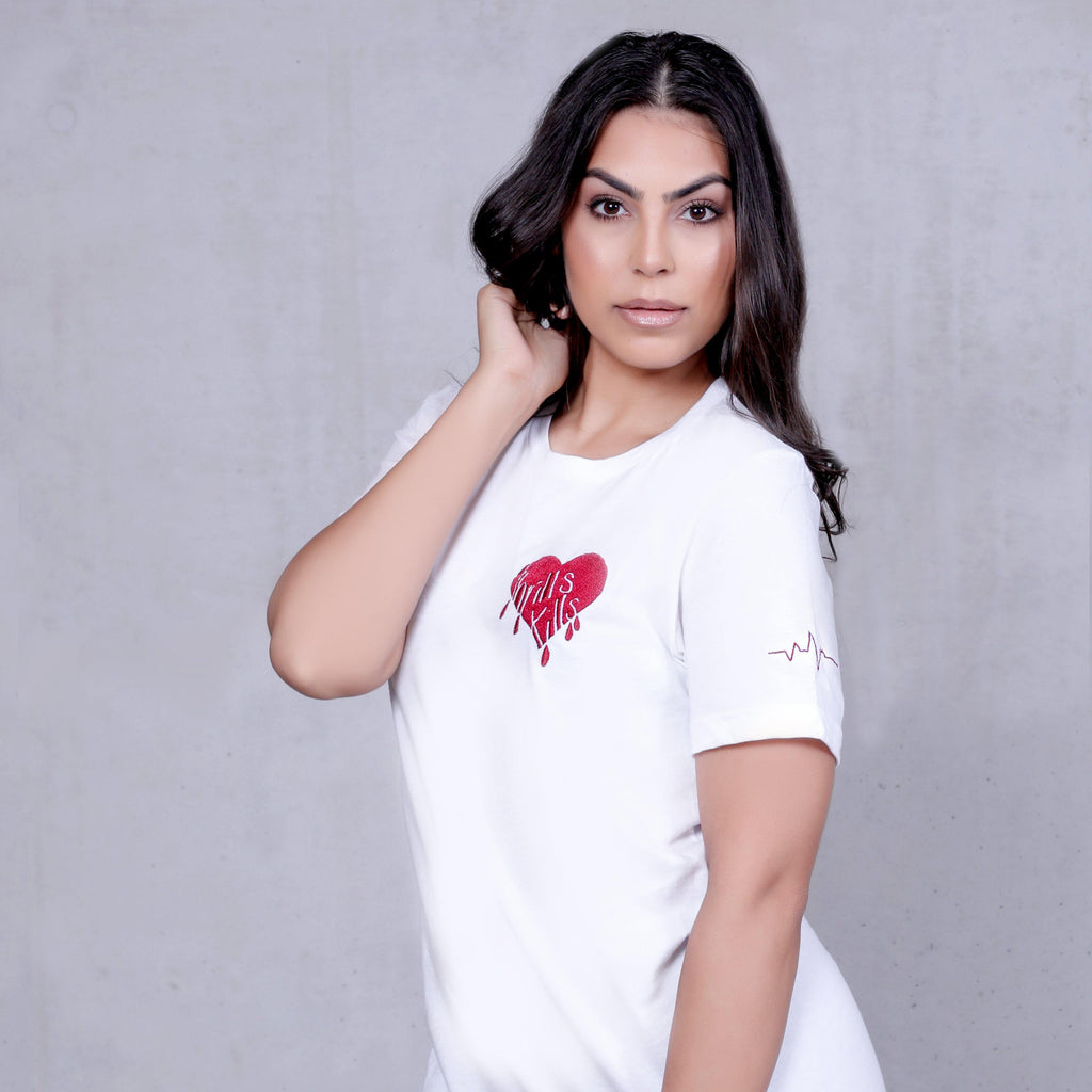 Kim Kardashian look a like modelling wearing a white oversized casual t-shirt with a heart design embroidered on left chest side with blood drops coming down stating thrills kills