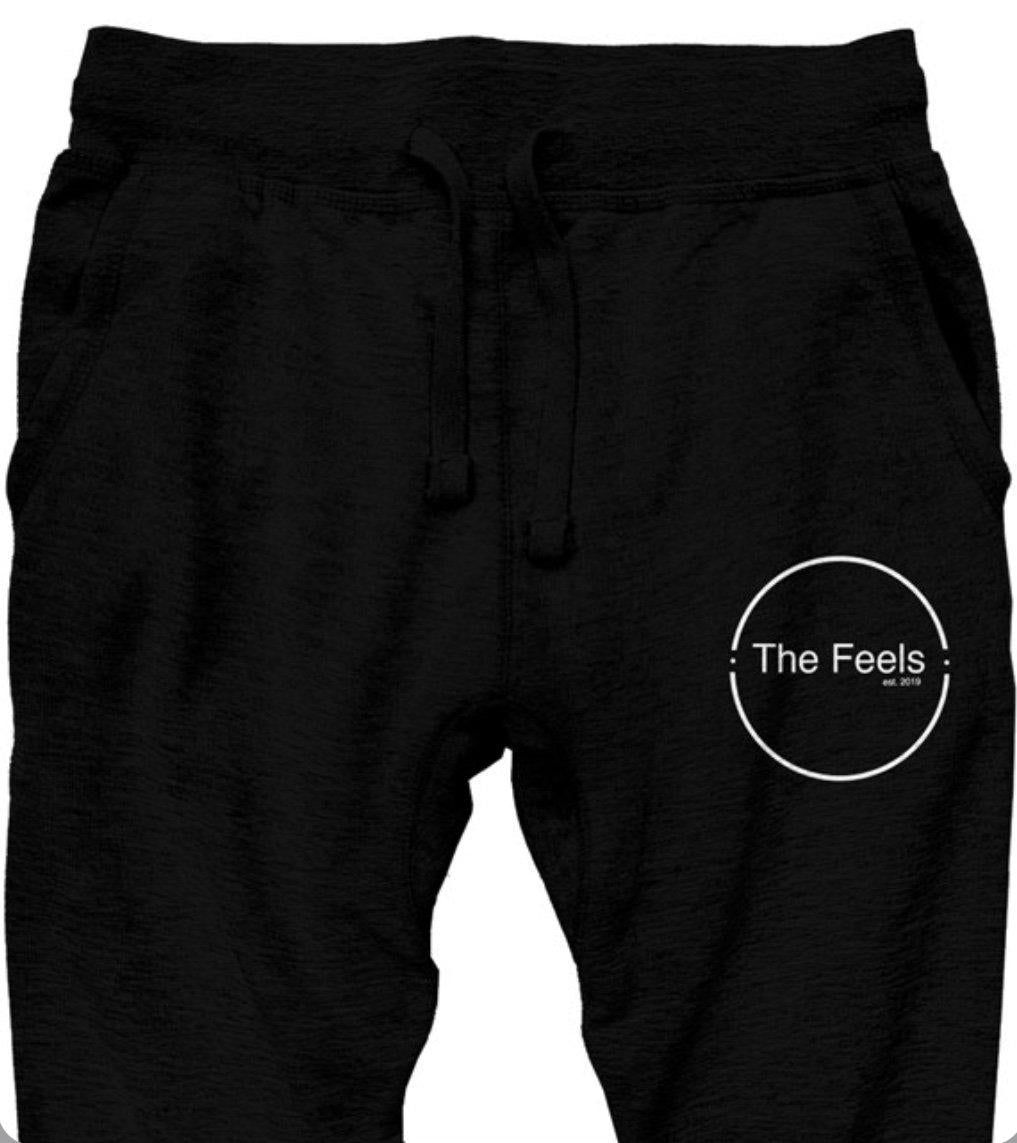 Close up of Supreme Black Sweatpants With Embroidered Logo and white embroidery on left side with a plain background